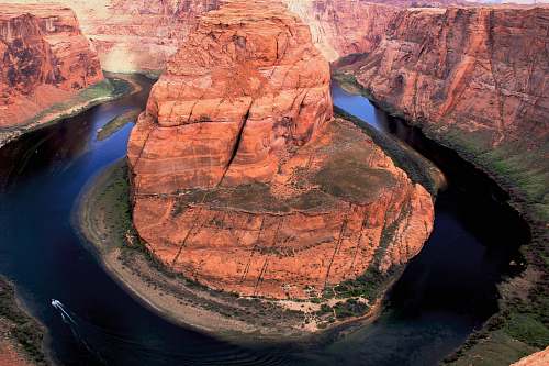 outdoors aerial photo of rock formation surrounded by body of water mountain