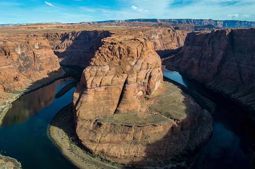 outdoors aerial photography of brown and green mountain surrounded by body of water during daytime mountain