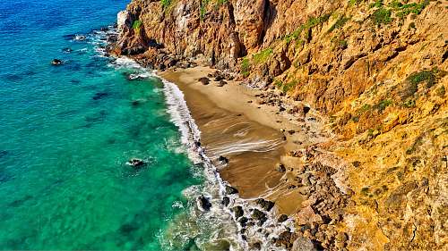 shoreline aerial photography of rock formation beside body of water water