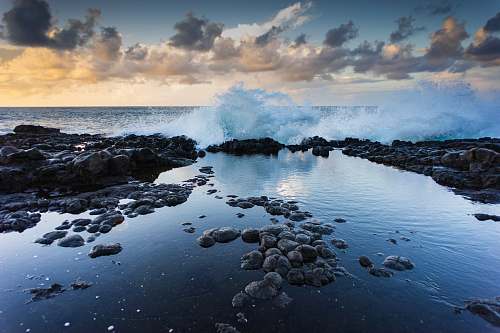 water landscape photography of rocks and barrel wave ocean