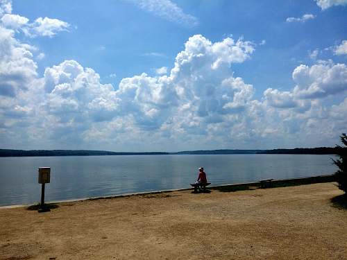 outdoors man sitting in front of body of water weather