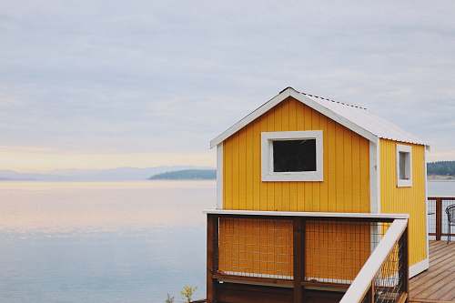 building white and orange house near water during daytime countryside