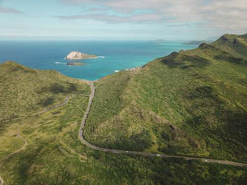 sea aerial photograph of mountain besides body of water water