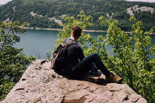 person person with backpack sitting on gray rock human