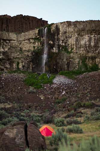 person waterfalls on rock formation at daytime human