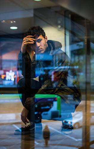 human man in black hoodie sitting near window des moines