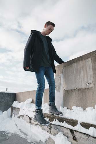 human man standing beside wall cover by snow people