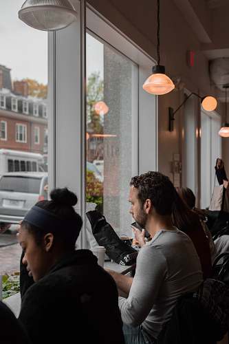 human people sits by the table facing windows sitting