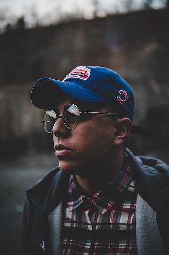 human shallow focus photography of man wearing blue fitted cap people