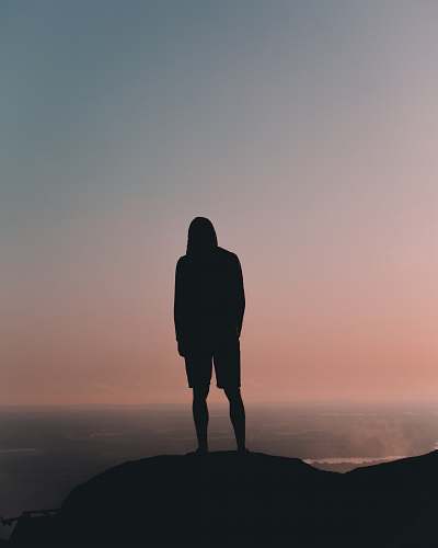 human silhouette man standing on mountain under gray sky silhouette