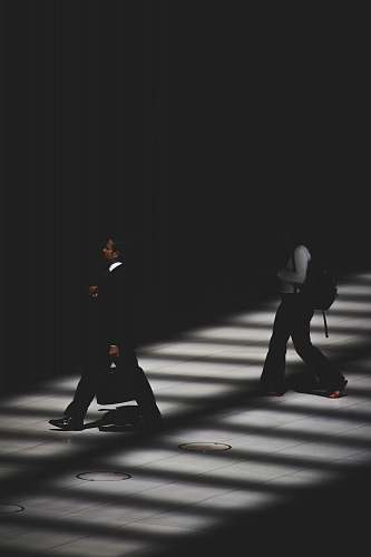 black-and-white two person walking inside building with black lighting people