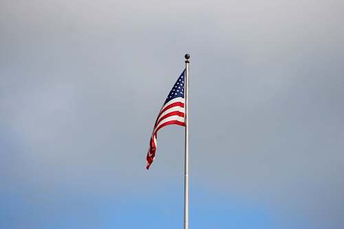 flag waving US flag under grey cloudy sky emblem