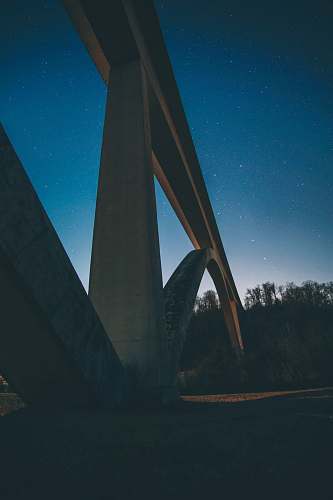 overpass close-up photography of concrete suspension bridge during nighttime freeway