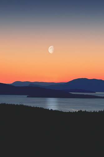 nature silhouette of mountains next to body of water moon