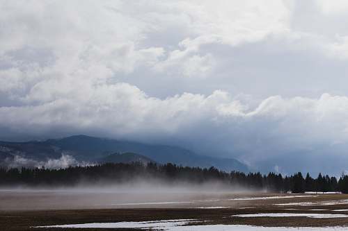 cloud trees near mountain under white clouds during daytime weather