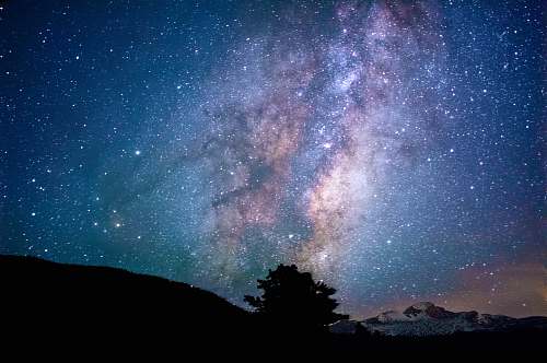 night silhouette of trees and mountain under blue sky at nighttime astronomy