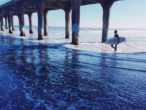 sea man walking while carrying surfboard ocean