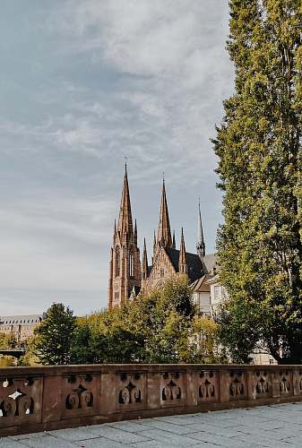 building beige concrete building with towers surrounded by trees during daytime spire