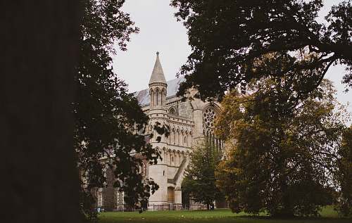 building beige house surrounded by tress spire