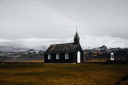building black and white wooden house in brown field spire