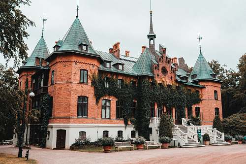 building brown castle surrounded with tall and green trees spire