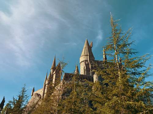 building brown castle under white clouds spire