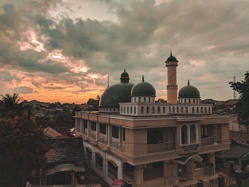 building brown concrete mosque surrounded by trees during sunset dome