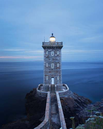 building brown lighthouse near body of water during daytime tower