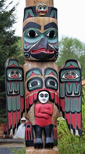 building brown, red, and black totem pole near trees emblem