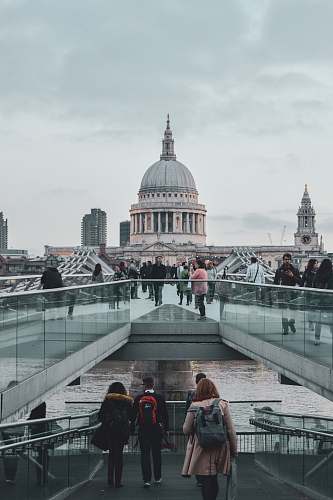 building crowd walking on pathway near dome building under dramatic clouds during daytime dome
