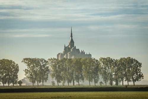 building gray castle surrounded by trees spire
