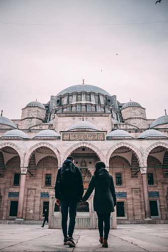 building man and woman holding hands near building dome