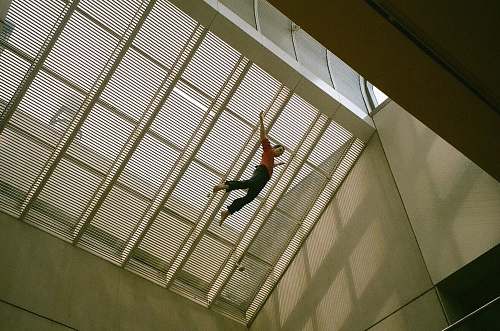 building man jumping on air at daytime window