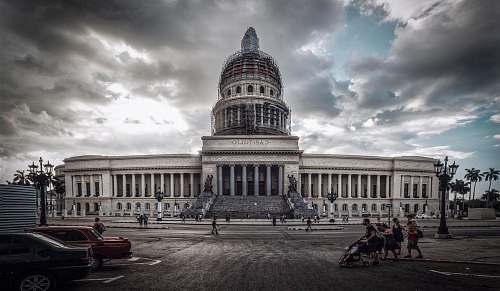 building people and cars in front of building dome