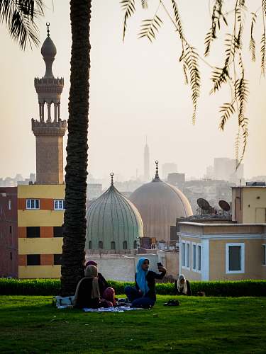 building people sitting on grass near mosque dome