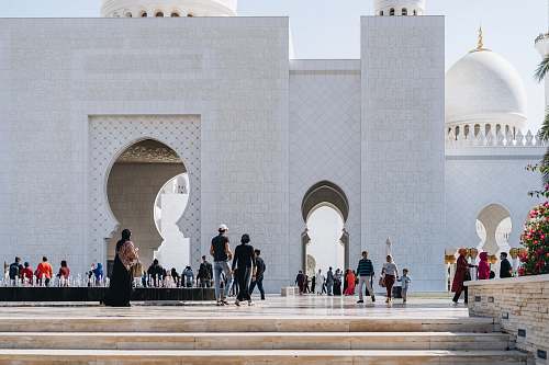 building people walking beside white mosque walls dome