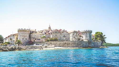 castle photo of gray concrete establishment near the body of water urban