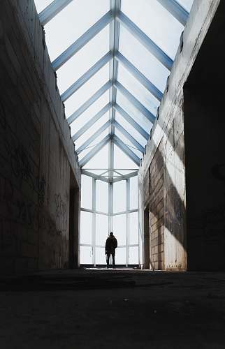 building silhouette of man standing inside abandoned building window