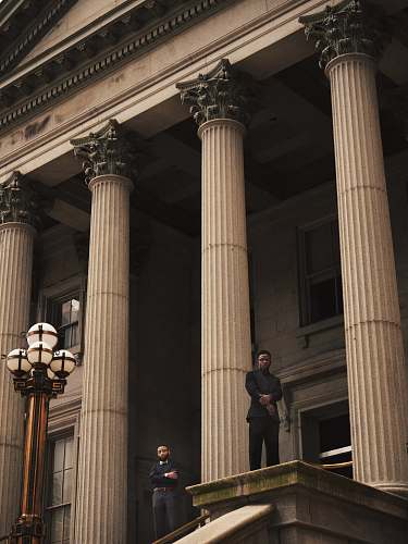 building two men standing on Corinthian column building pillar