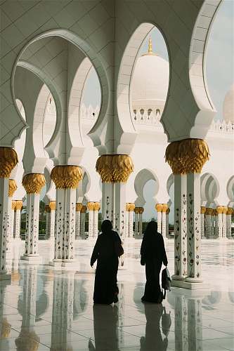 building two women standing near white pillars dome