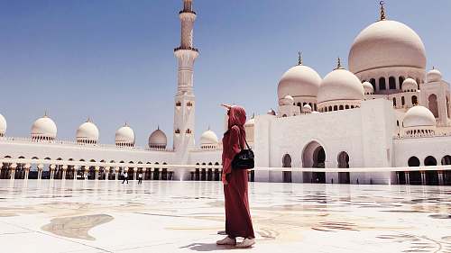 building woman in red dress walking near mosque dome