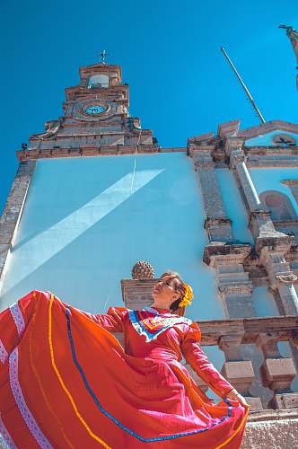 building woman wearing orange dress near church tower
