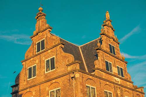 architecture brown brick building under blue sky spire