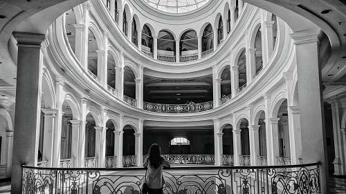 architecture woman standing beside balustrade black-and-white