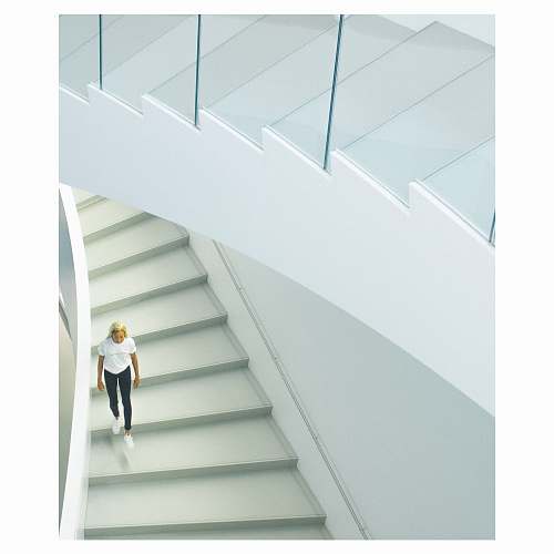 staircase woman wearing white crew-neck t-shirt walking on stairs banister