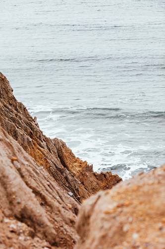  brown rock formation beside body of water during daytime 