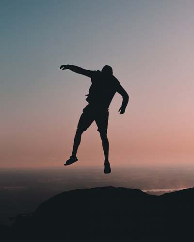 gliding silhouette of man jumping on cliff at golden hour leisure activities