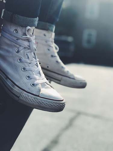 clothing low-angle photography of person wearing white mid-high sneakers footwear