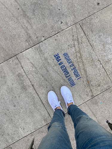 clothing person in blue denim jeans and white sneakers standing on gray concrete floor footwear