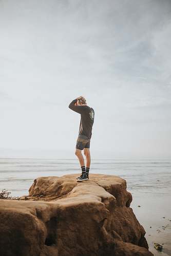 clothing person standing on rock formation during daytime shorts